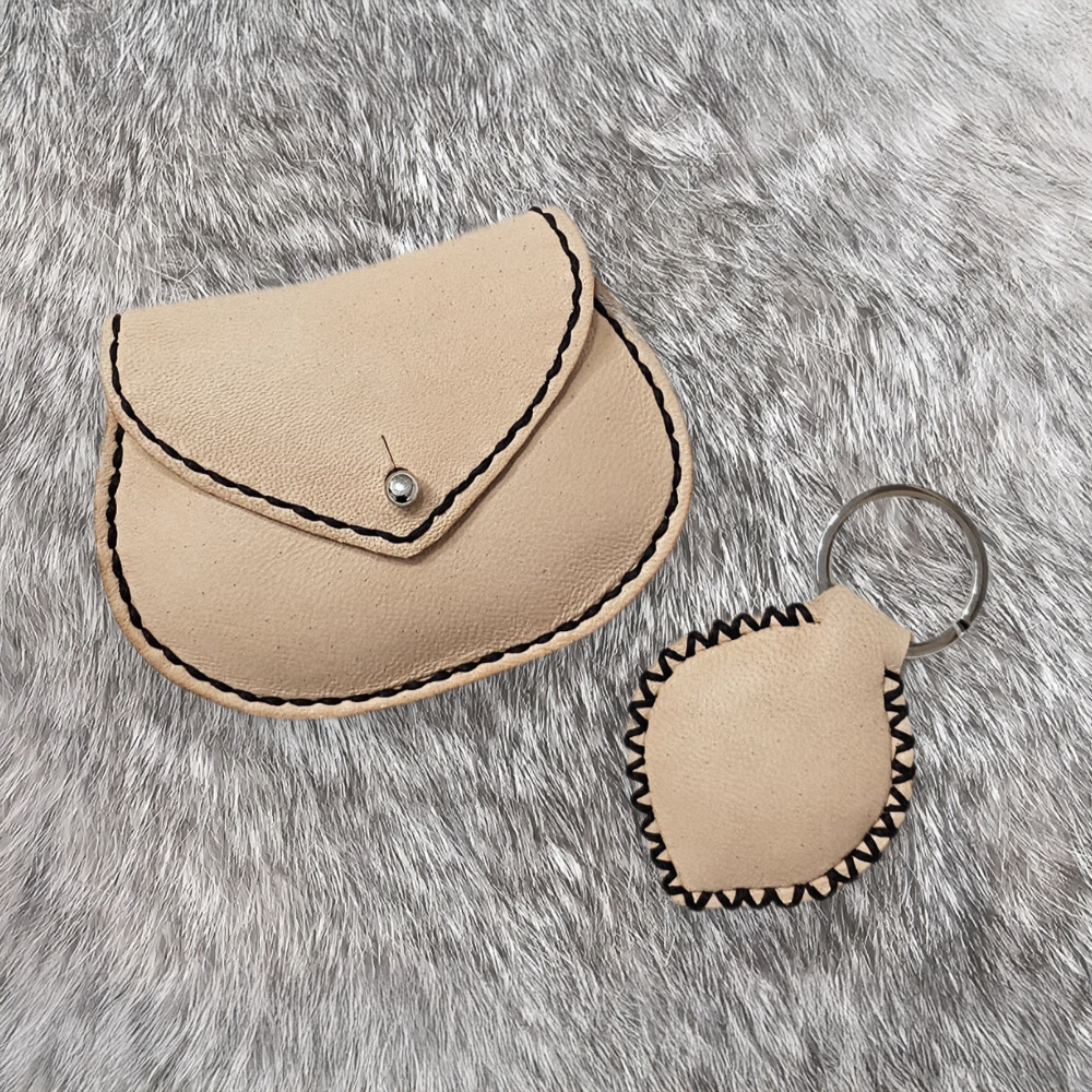 monedero y llavero cosidos a mano de color beis colocados sobre una piel de pelo gris