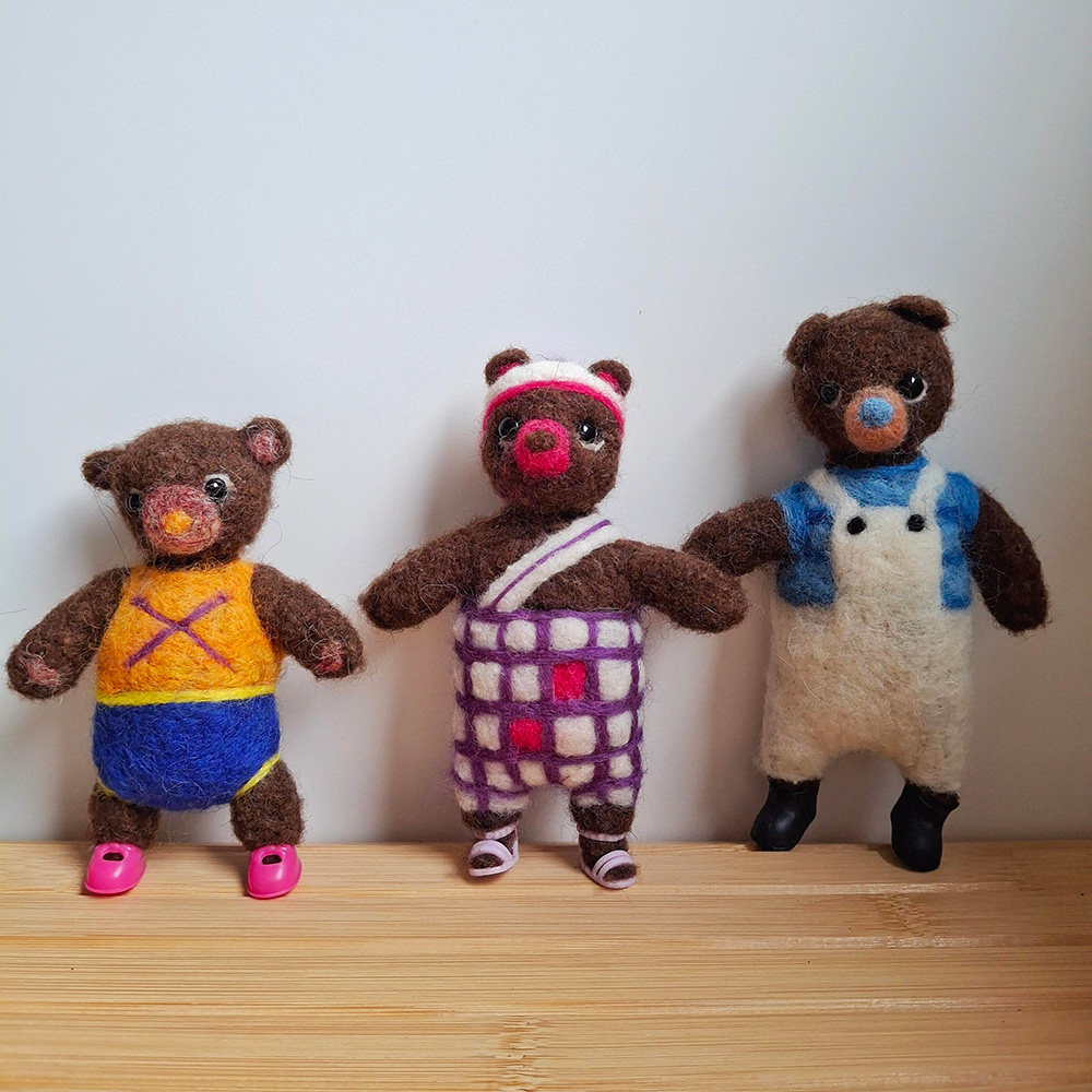 tres ositos vestidos con ropa llamativa completamente elaborados con lana fieltrada