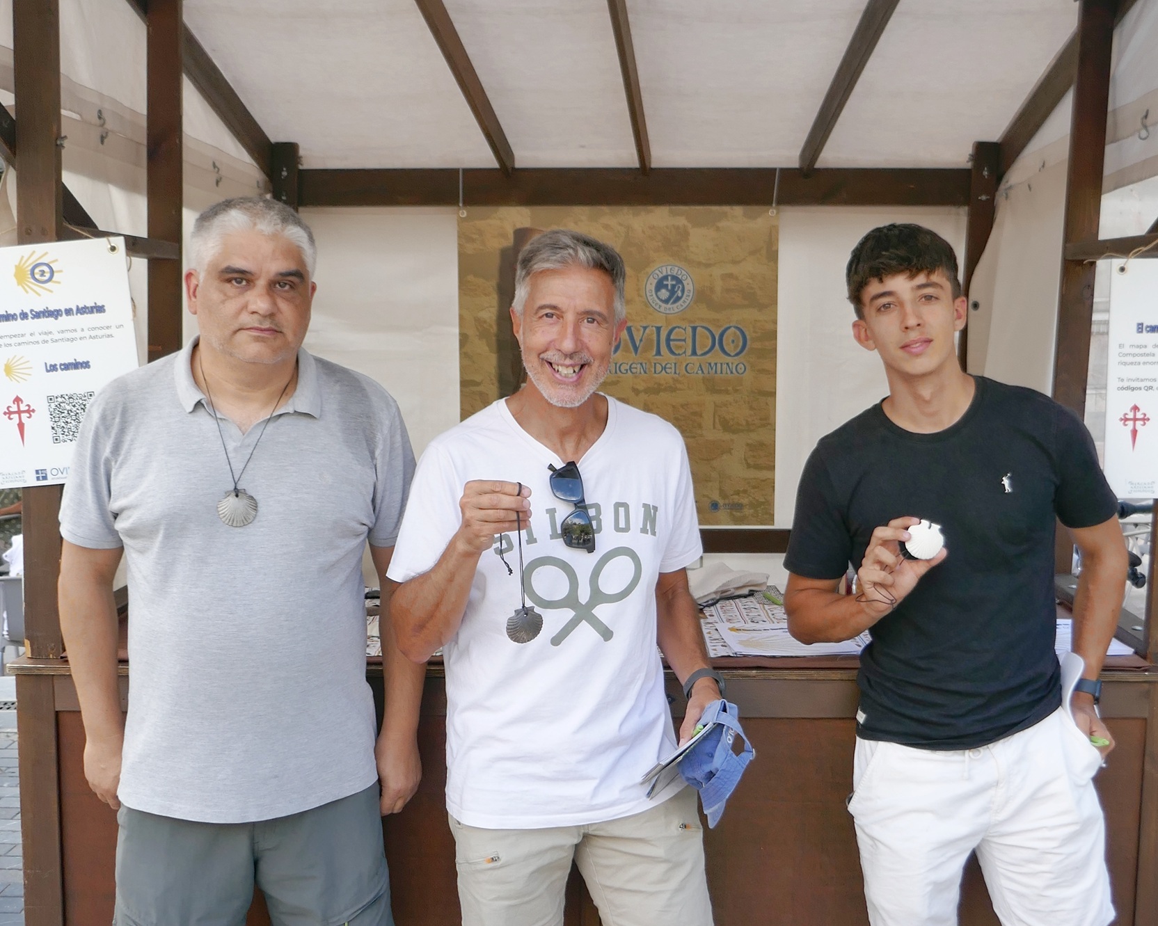 tres hombres posan frente al puesto del camino primitivo en el mae de Oviedo